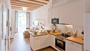 Una cucina moderna con mobili bianchi, travi in legno, forno integrato e lavello.
