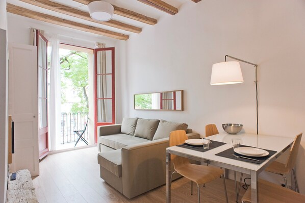 Ein modernes Wohnzimmer mit einer Couch, einem Esstisch, Stühlen und einer Lampe.