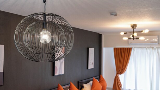A modern hotel room with a large bed, orange pillows, a hanging spherical light fixture, and a ceiling fan. - Seeds Nipponbashi (Osaka)