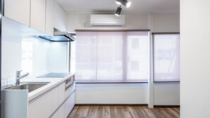 A modern kitchen with white cabinets, a stainless steel sink, and a built-in oven. - Seeds Nipponbashi (Osaka)