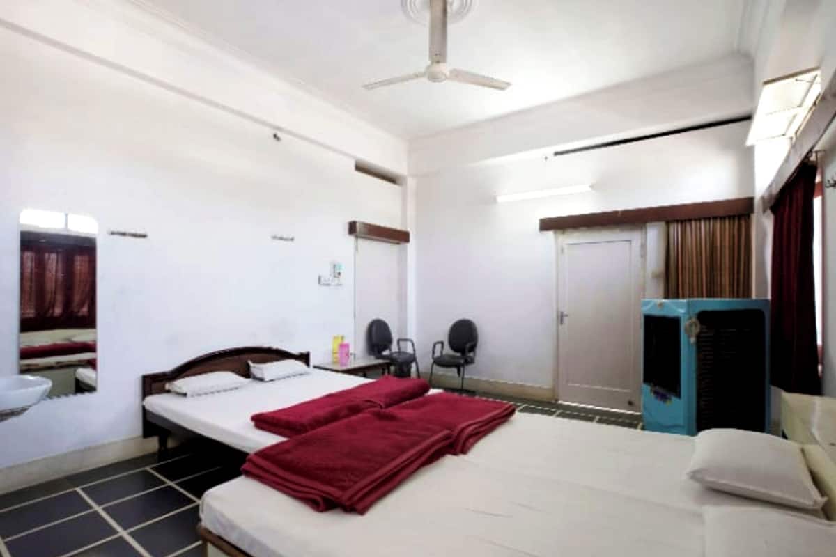 Une chambre d’hôtel comprenant un lit, un ventilateur de plafond, une armoire, un bureau avec une chaise et un miroir.