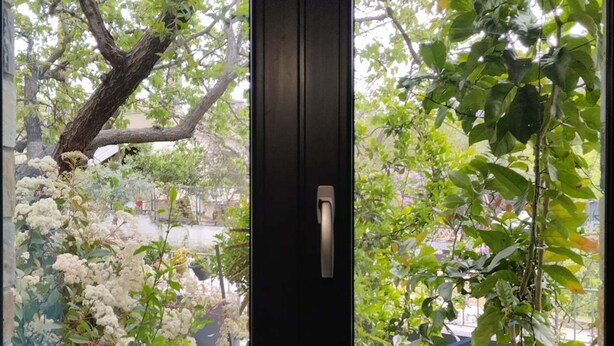 A door with a view of a garden through a window. - Mona Lisa Guest House (Volos)