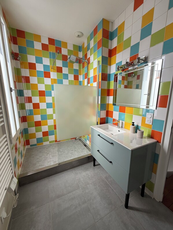 A bathroom with colorful checkered tiles, a shower, a sink with a mirror, and a toilet. - Charming house Cholet (20mnPuy du Fou) (Cholet)