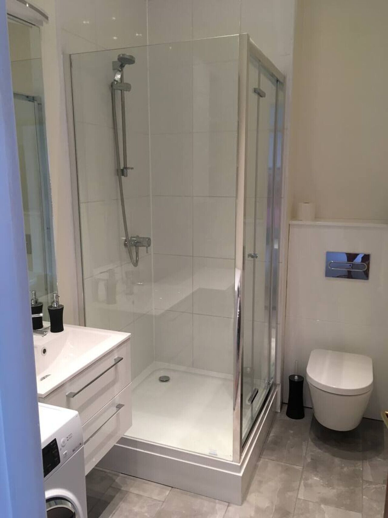 A modern bathroom with a glass-enclosed shower, a white toilet, and a sink with a mirror.