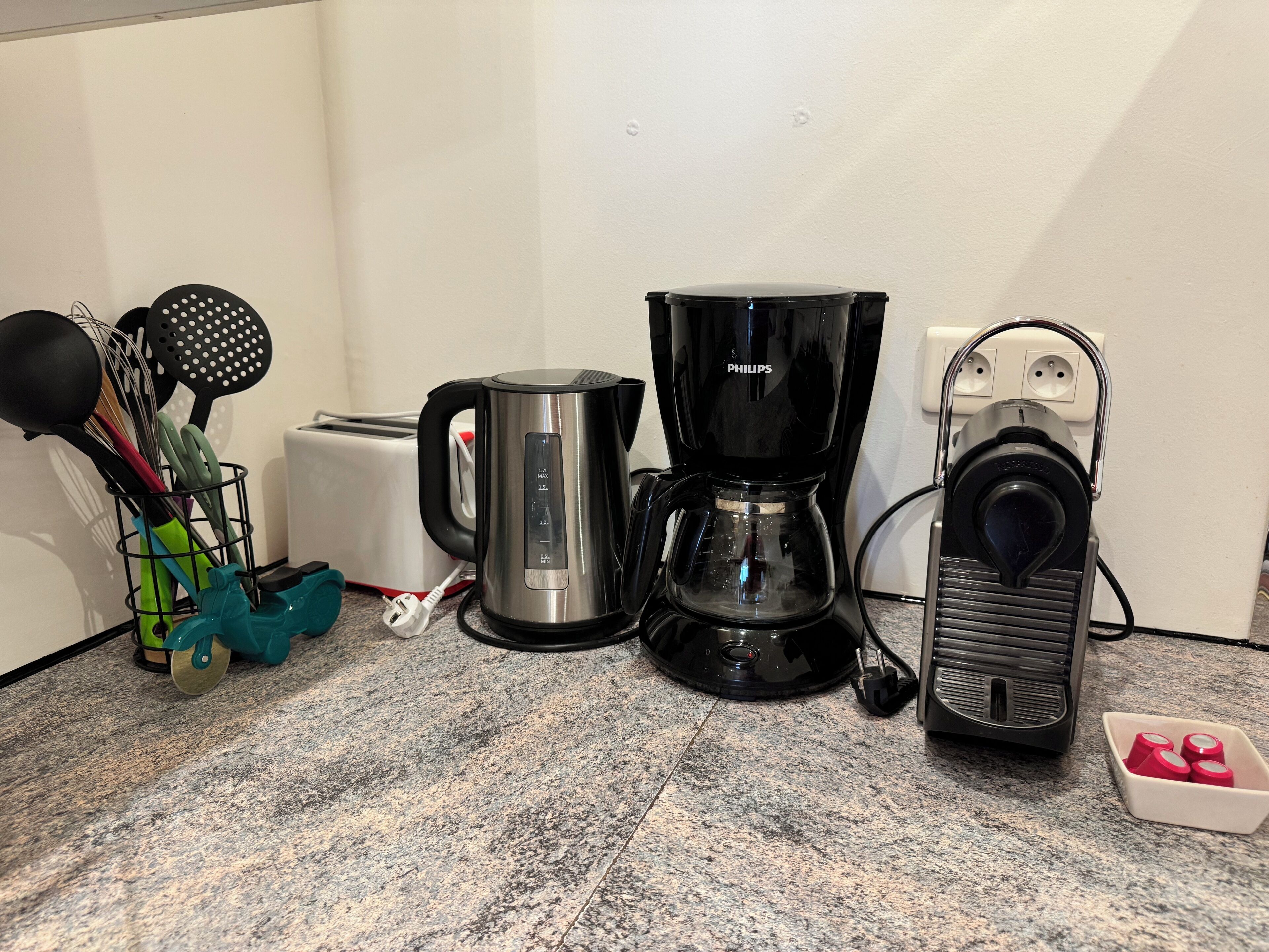 Un plan de travail de cuisine avec un grille-pain, une machine à café, une bouilloire et un mixeur.