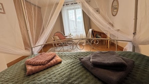 Un dormitorio con una cama, una silla, una mesa y un ventanal.
