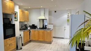 Una cocina moderna con armarios de madera, horno empotrado, cafetera y radiador blanco.