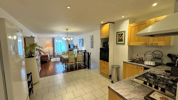 Una cocina moderna con estufa a gas, armarios de madera y una zona de comedor con mesa y sillas.