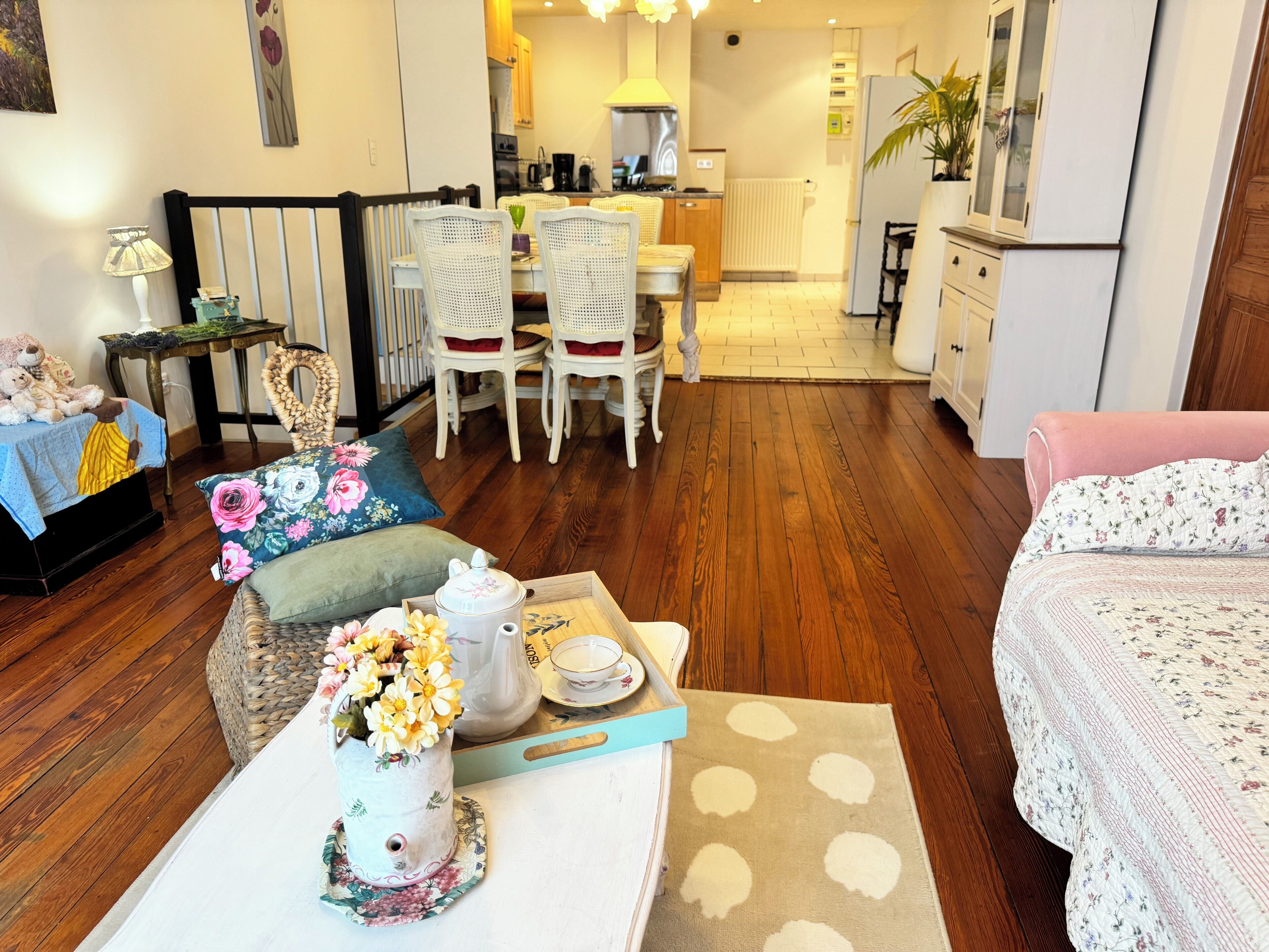 A cozy living room with a dining area, wooden flooring, and a kitchen in the background.
