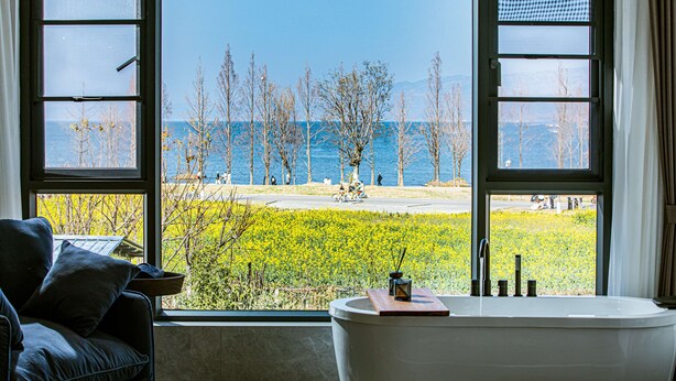 A room with a large window offering a view of a lake and trees.