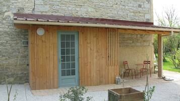 A rustic building with a wooden exterior, a blue door, and a small patio area with outdoor seating.