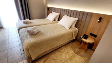 Ein Hotelzimmer mit zwei Betten, einem Nachttisch mit Telefon und einer Wandleuchte.