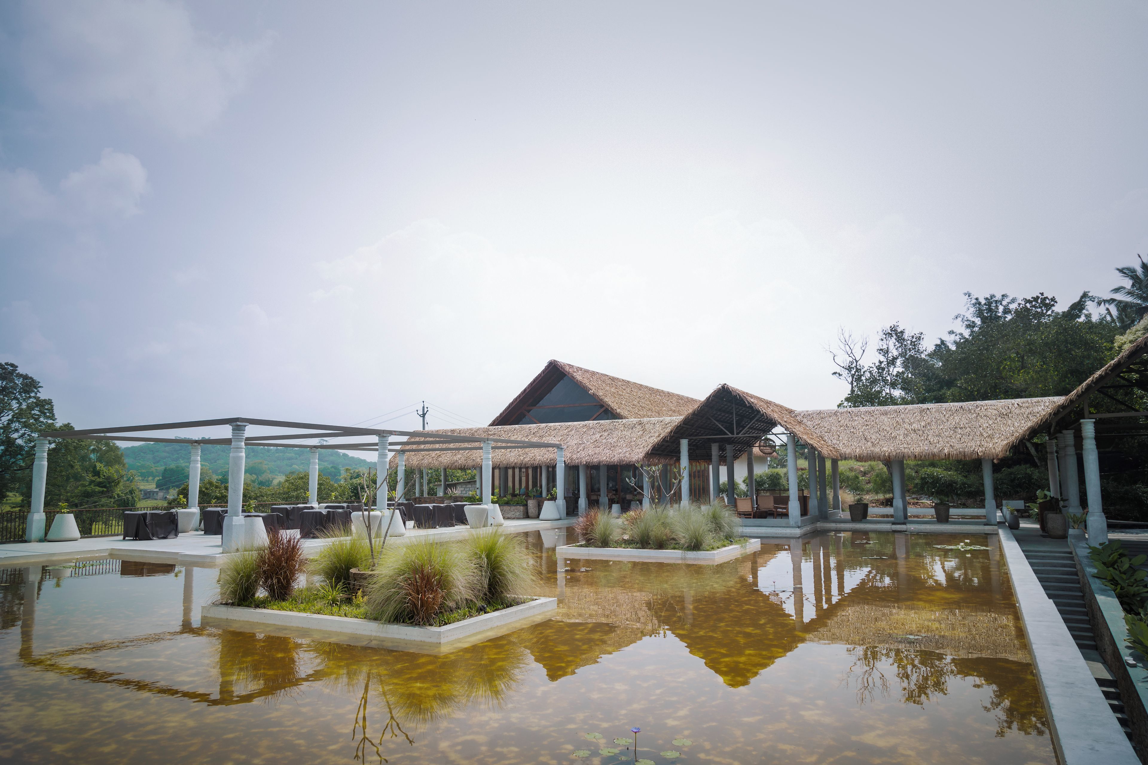 A resort with outdoor seating, a pool, and a thatched-roof structure.
