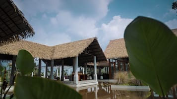 A resort with thatched-roof structures, a pool, and lush greenery.