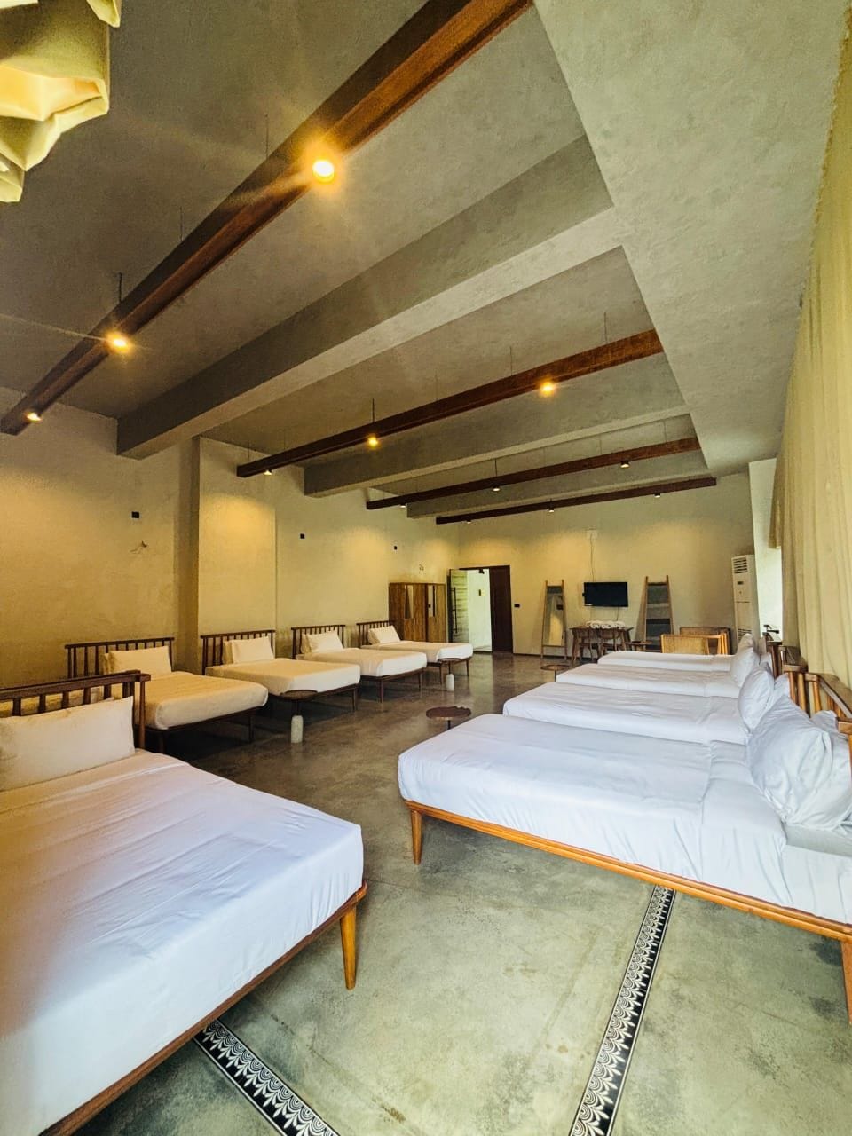 A hotel room with multiple beds, a wooden ceiling, and a large mirror.