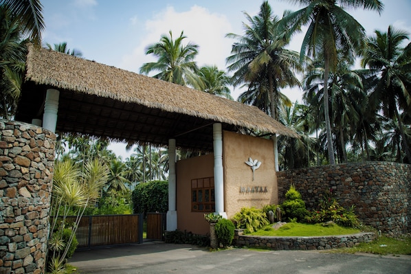 Un edificio con techo de paja y paredes de piedra, rodeado de palmeras.