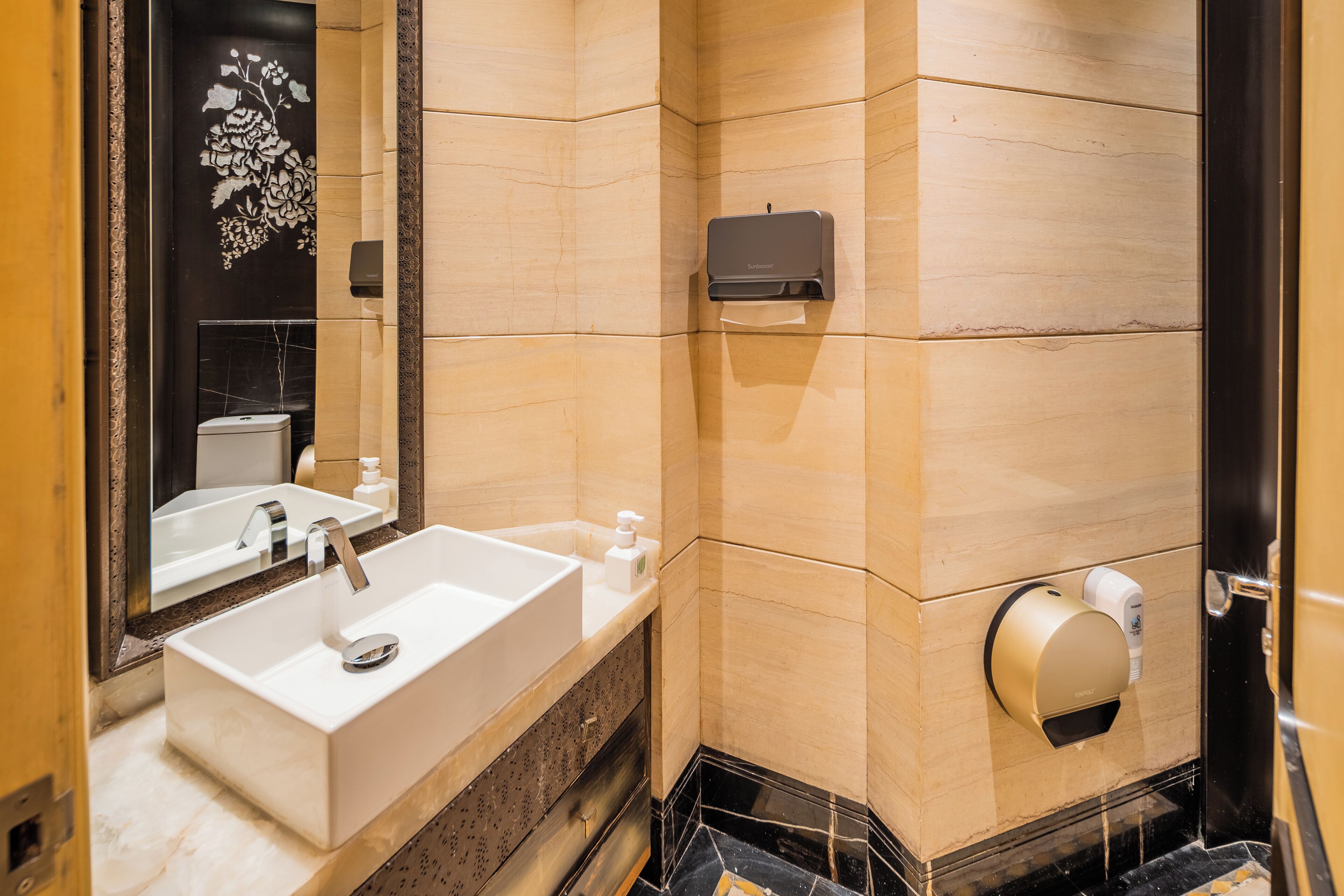 A modern bathroom with a large sink, mirror, and two hand dryers.