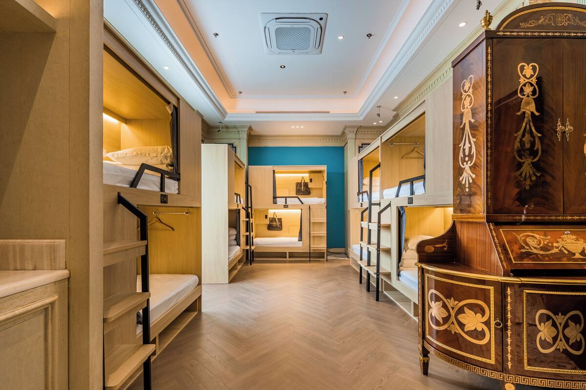 A hotel corridor with bunk beds, a wooden wardrobe, and a blue wall.