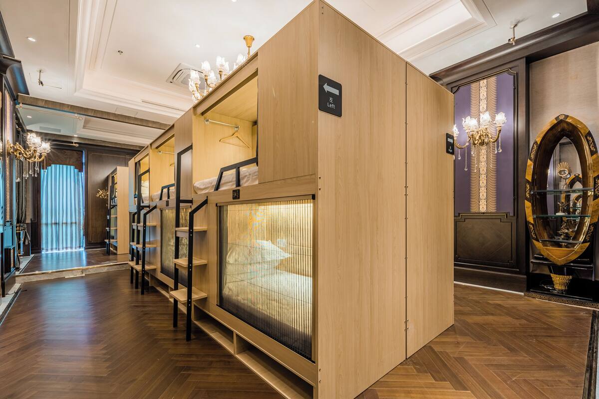 A hotel room with a bunk bed, a large mirror, and a chandelier.