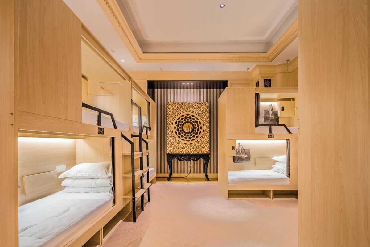 A hotel room with bunk beds, a decorative wall, and a small table.