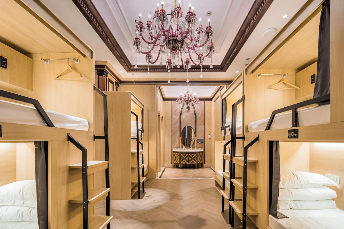 A hotel room with bunk beds, a chandelier, and a vanity with a mirror.