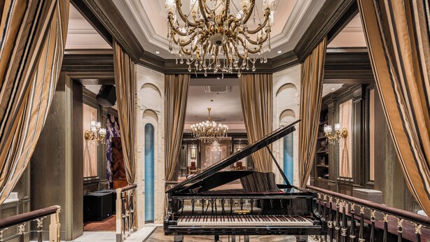 A grand piano in a luxurious room with ornate chandeliers and draped curtains. - Paris Hotel (Shanghai)