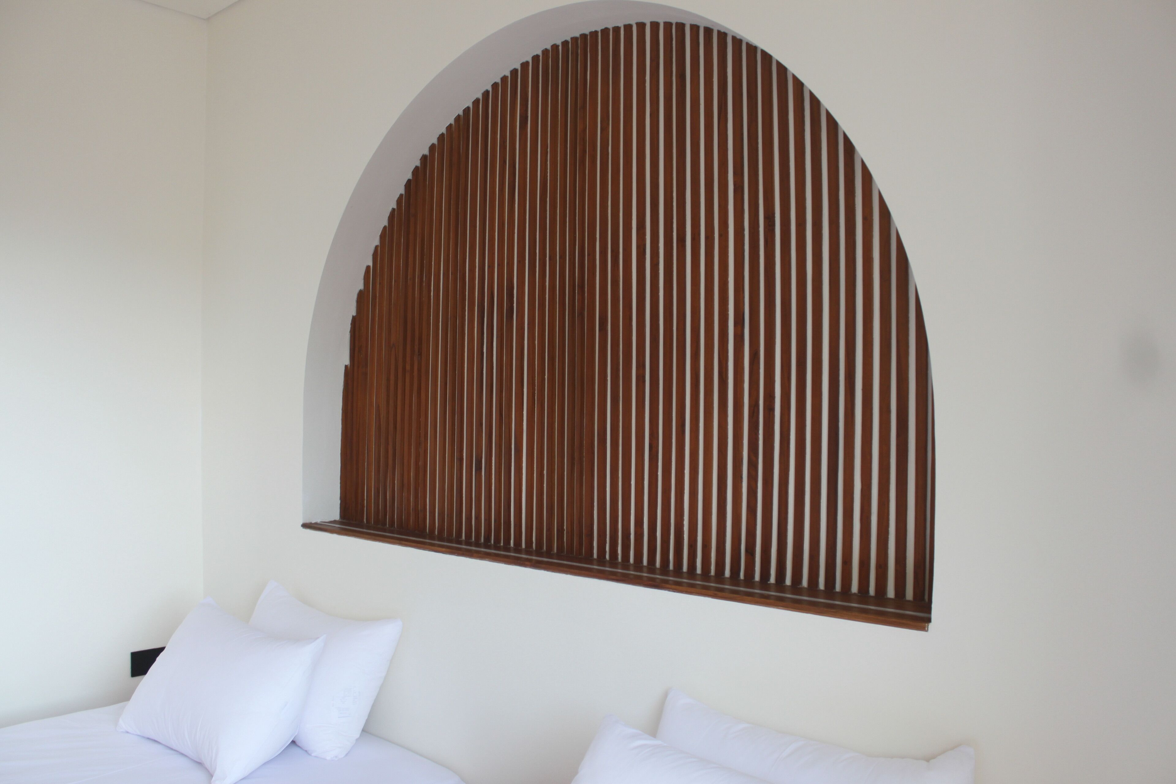 A bedroom with a bed, two pillows, and a wooden slat wall design.