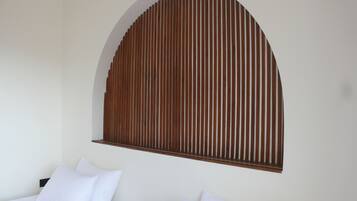 A bedroom with a bed, two pillows, and a wooden slat wall design.