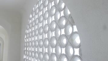 Un mur blanc orné d’un motif géométrique et comportant une série d’ouvertures circulaires.
