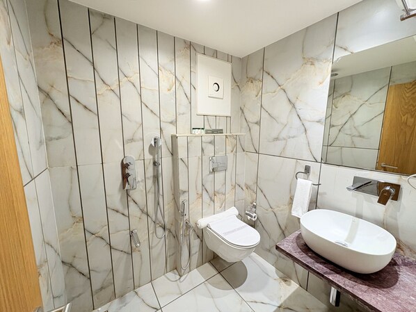 Une salle de bain avec un mur en marbre, des toilettes, une douche et un lavabo.