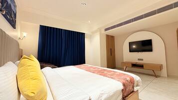 A modern hotel room with a large bed, a desk, and a TV mounted on the wall.