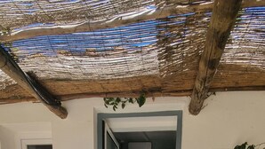 Ein modernes Haus mit Natursteinfassade, Holzbalkendecke und einer durch einen offenen Durchgang einsehbarer Küche.