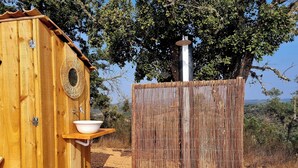 A wooden outhouse with a built-in sink and a mirror, surrounded by a bamboo fence. - Lotus Glamping Tent (São Luís)