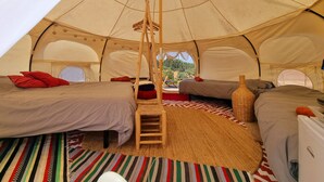 A spacious tent with two beds, a central wooden ladder, and a woven rug. - Lotus Glamping Tent (São Luís)