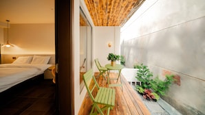 A bedroom with a wooden ceiling, a bed, and a nightstand. There is a small table with a plant and two chairs outside the room. - Cloud 9 Hotel (Luoyang)