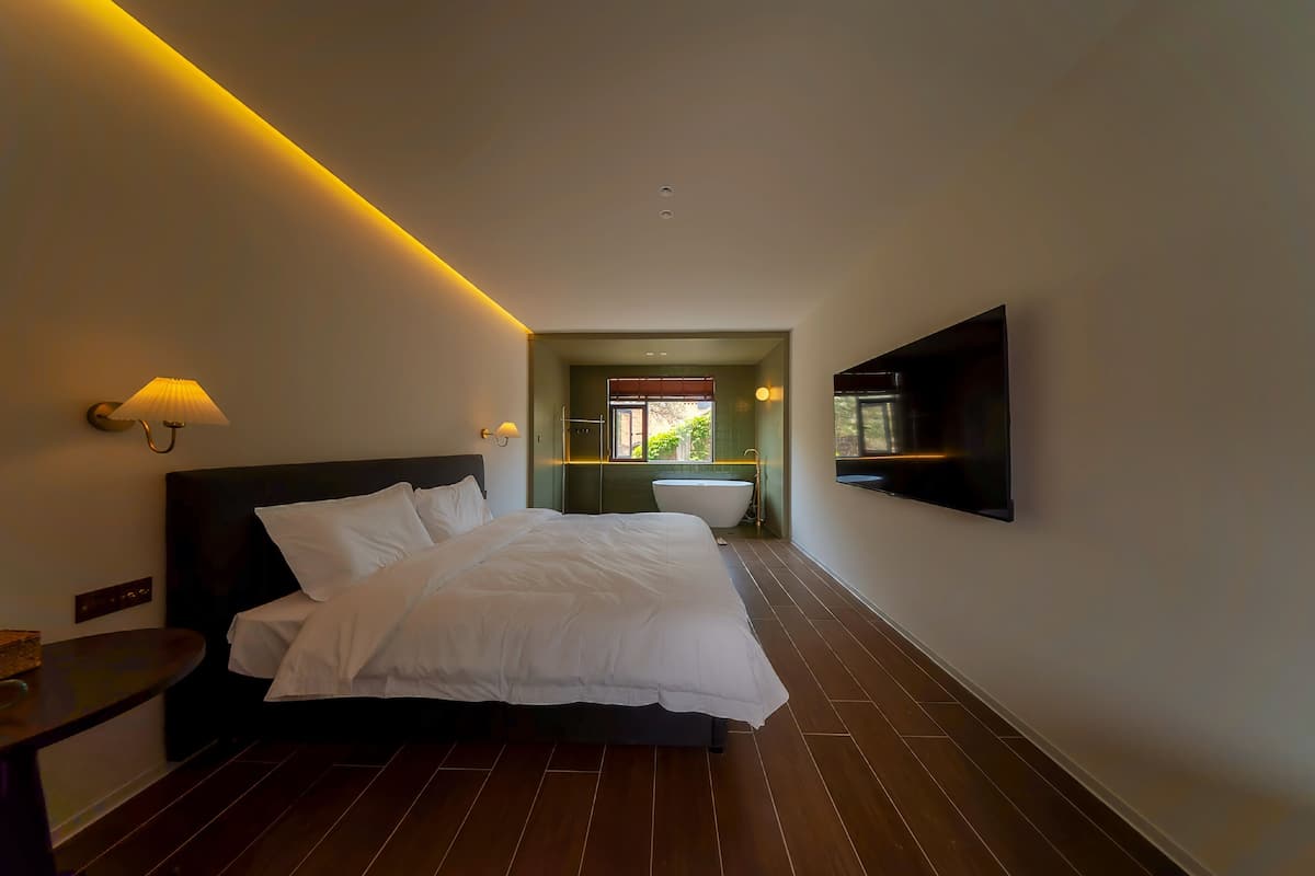 Quarto de hotel moderno com uma cama grande, televis ão de tela plana na parede e vista para o banheiro.