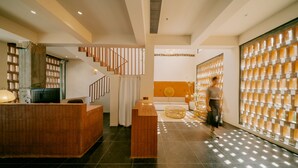 A reception area with a wooden reception desk, a staircase, and a wall with a patterned design. - Cloud 9 Hotel (Luoyang)