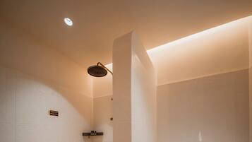 A modern bathroom with a toilet, shower, and sink.