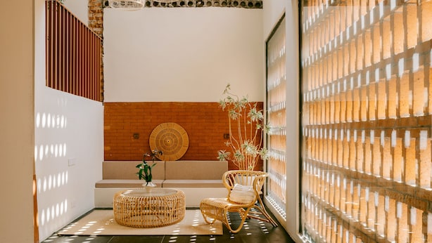 A room with a brick wall, a woven chair, a round table, and a plant. - Cloud 9 Hotel (Luoyang)