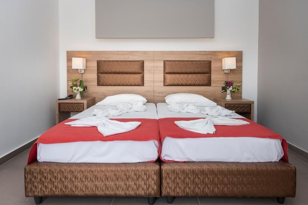 A double bed with a wooden headboard, two bedside tables with lamps, and a red bedspread.