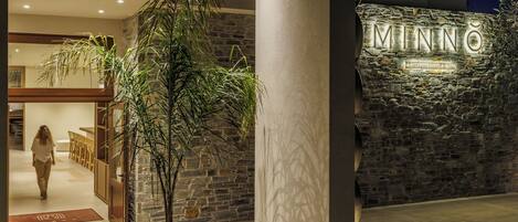 Entrada de un hotel con un muro de piedra y un cartel que dice 'MINNO Boutique Hotel & Spa'.