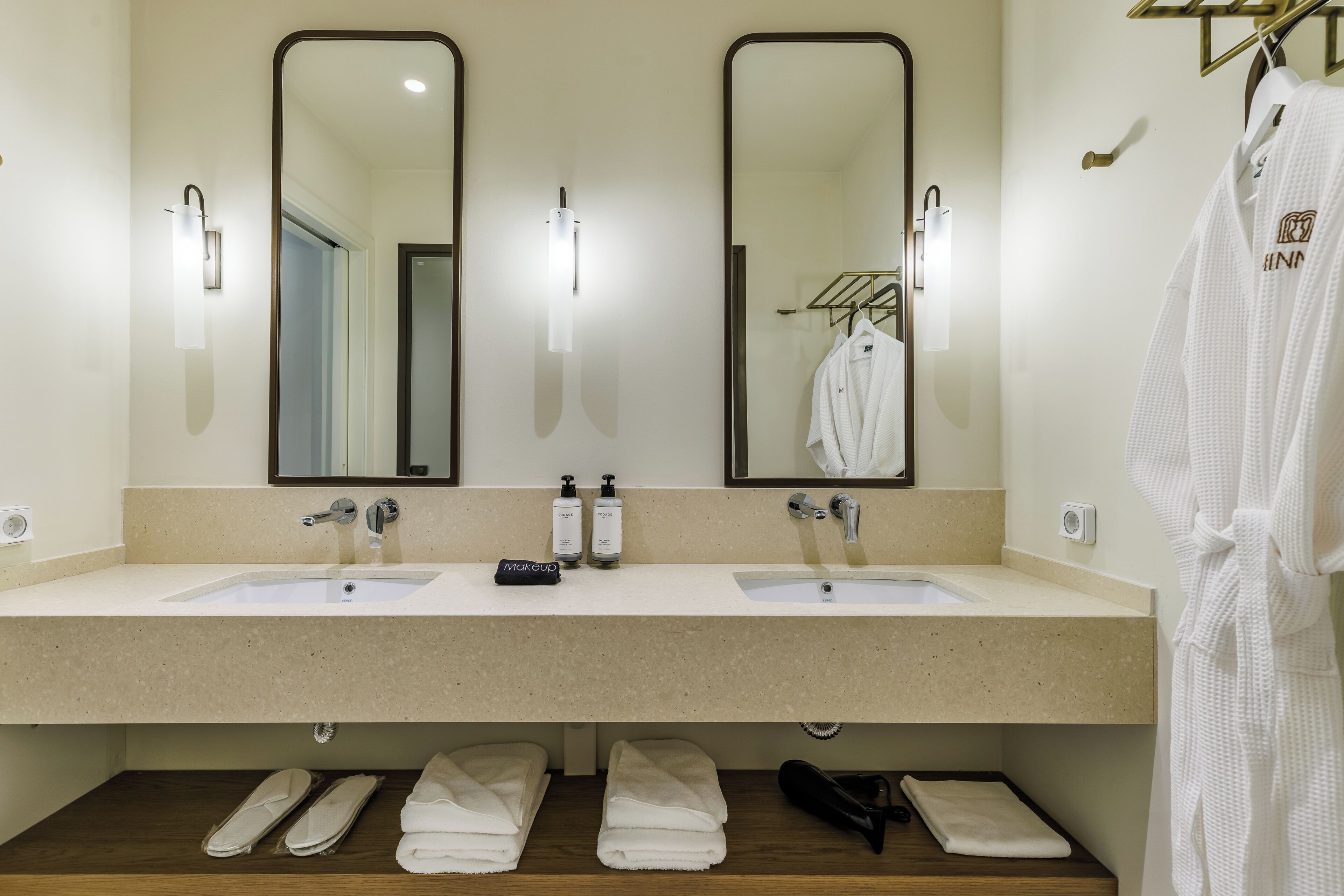 A bathroom with two sinks, a mirror, and a robe rack.