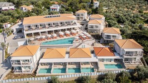 Un resort con varias edificaciones, una piscina central y zonas de estar al aire libre.