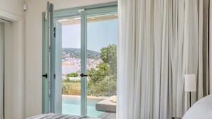 Un dormitorio con cama, vista a una piscina y puerta que da al exterior.