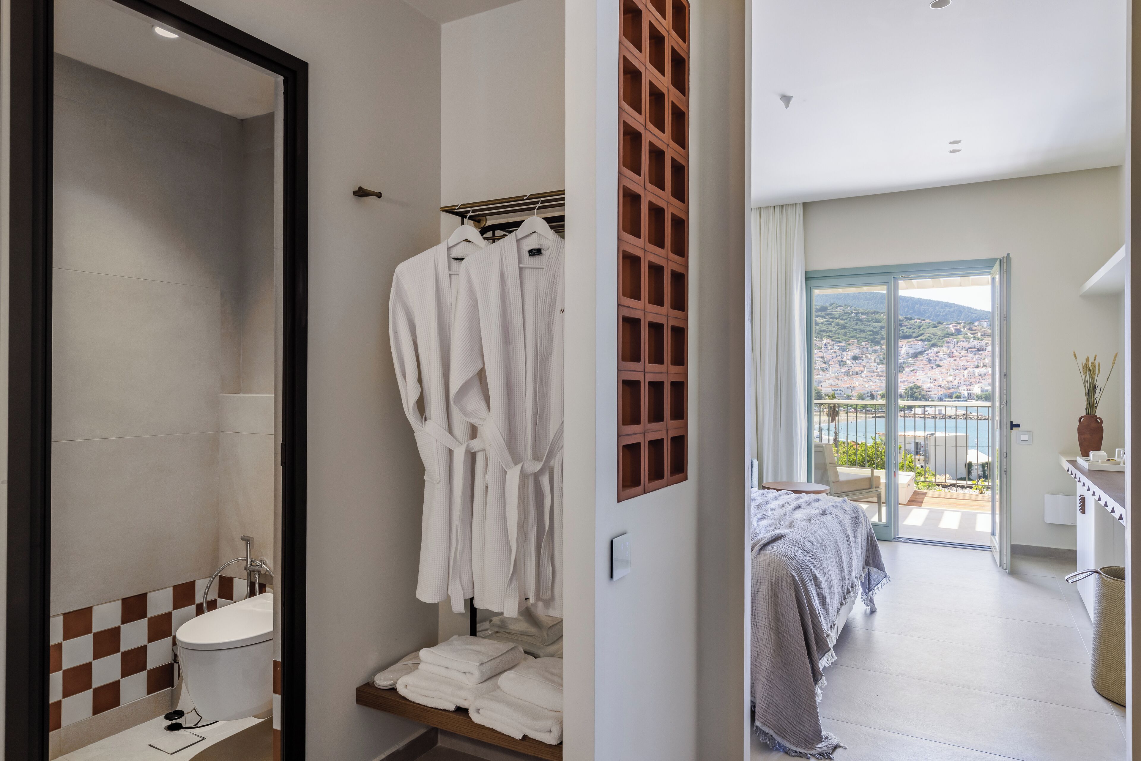 A modern bathroom with a bathtub, a towel rack with robes, and a checkered tile backsplash.