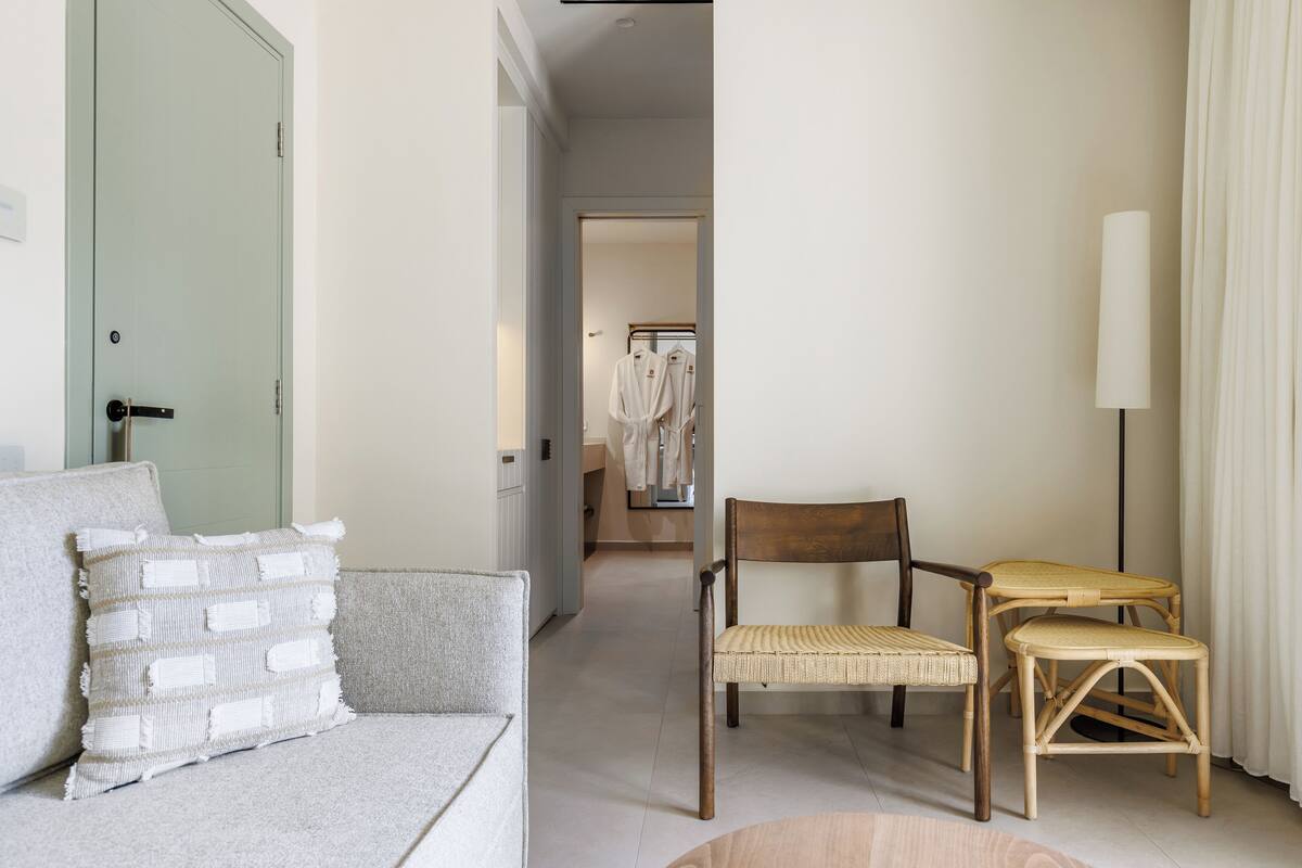 Habitación de hotel con sofá, una silla, una mesita y una lámpara.