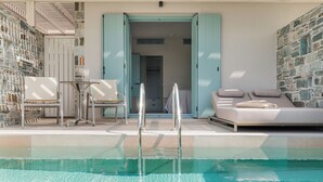 Zona de piscina con una silla de descanso, una mesa y una escalera que lleva a un espacio interior.