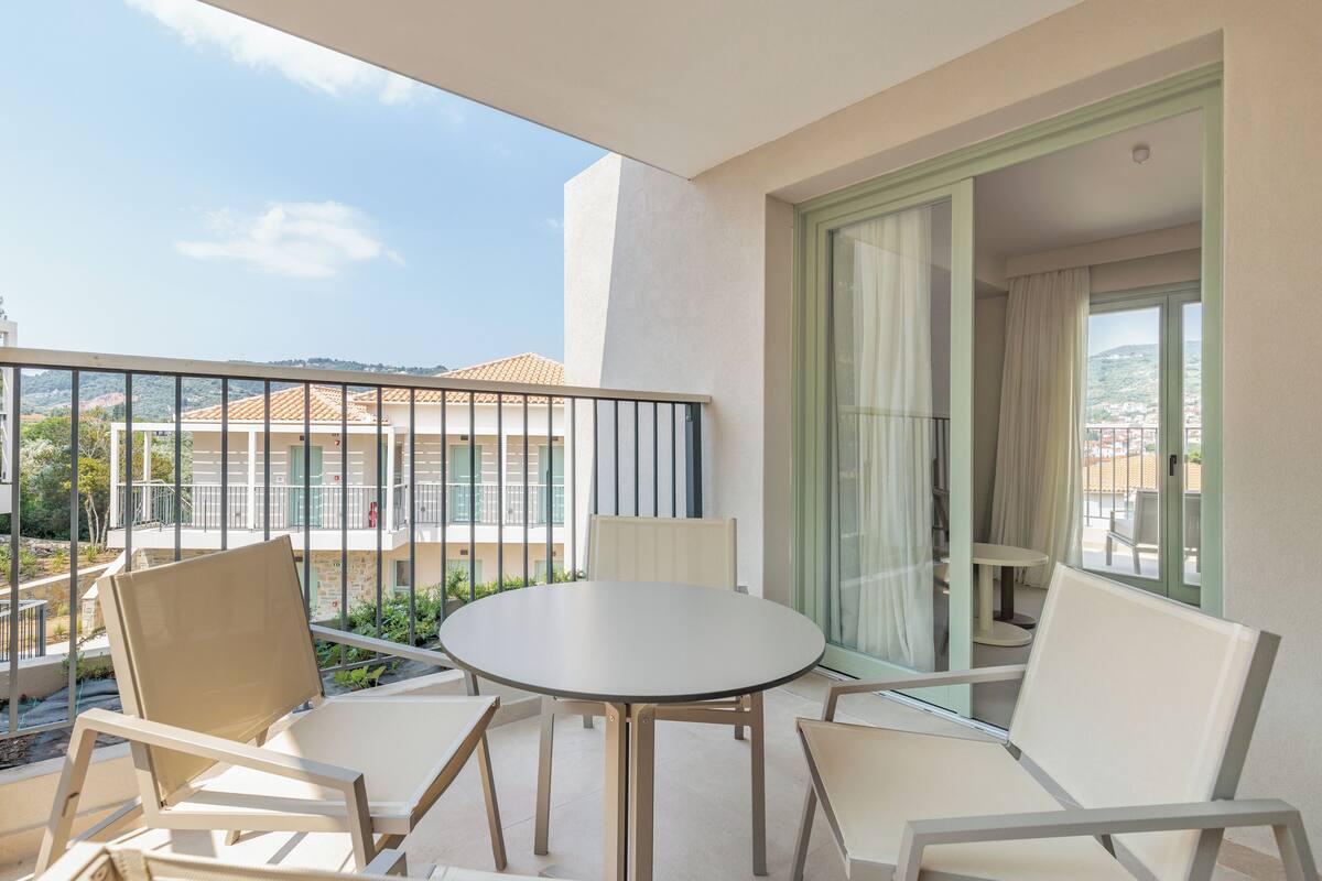 Un balcón con una mesa redonda y cuatro sillas, con vistas a una zona residencial con edificios y zonas verdes.