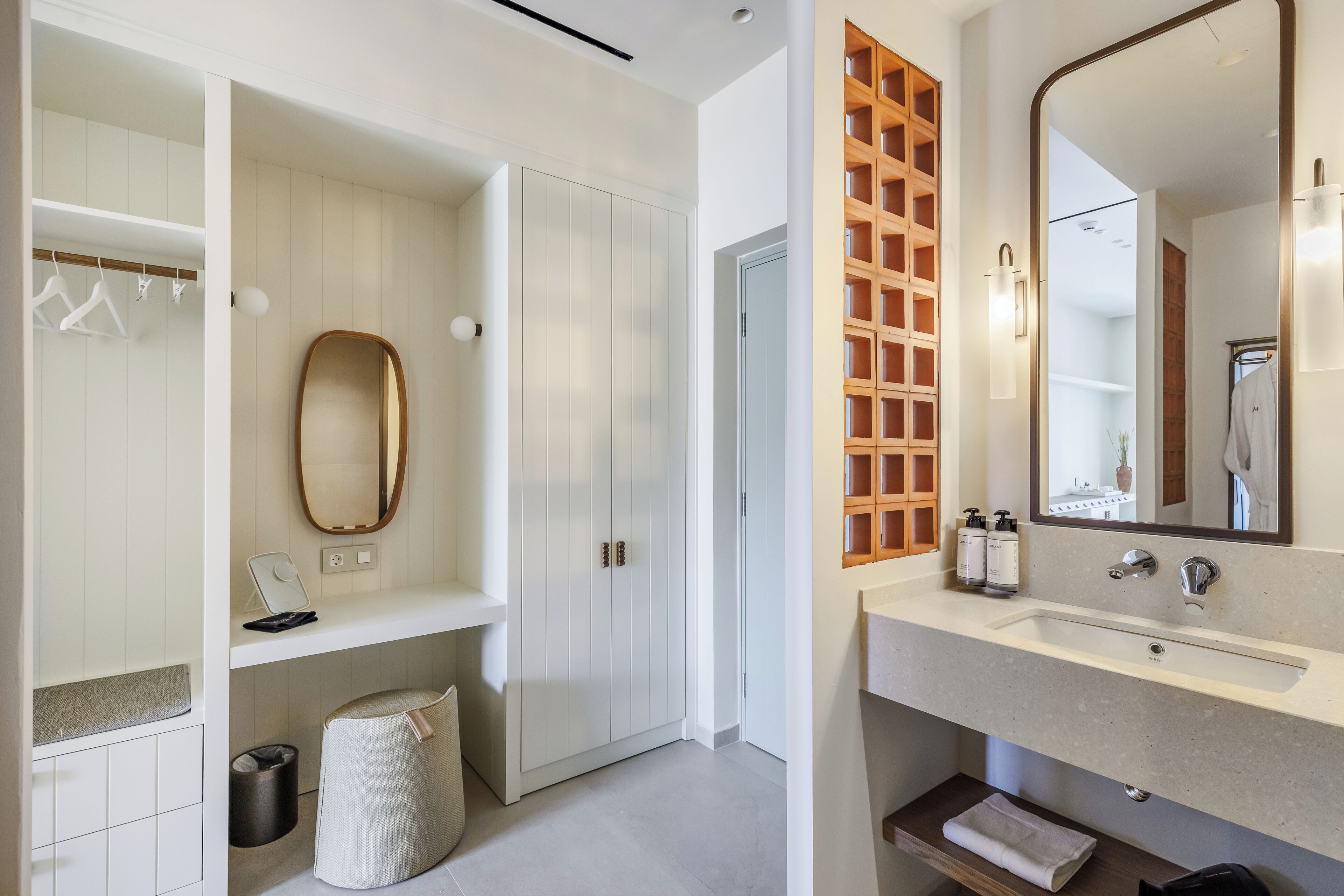 Un baño moderno con tocador, espejo y armarios de almacenamiento.
