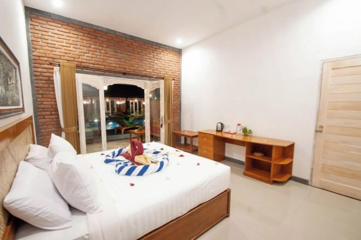 A bedroom with a bed, a desk, a wardrobe, and a brick wall.